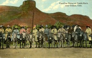 people posing with donkeys in front of Golden's Castle Rock